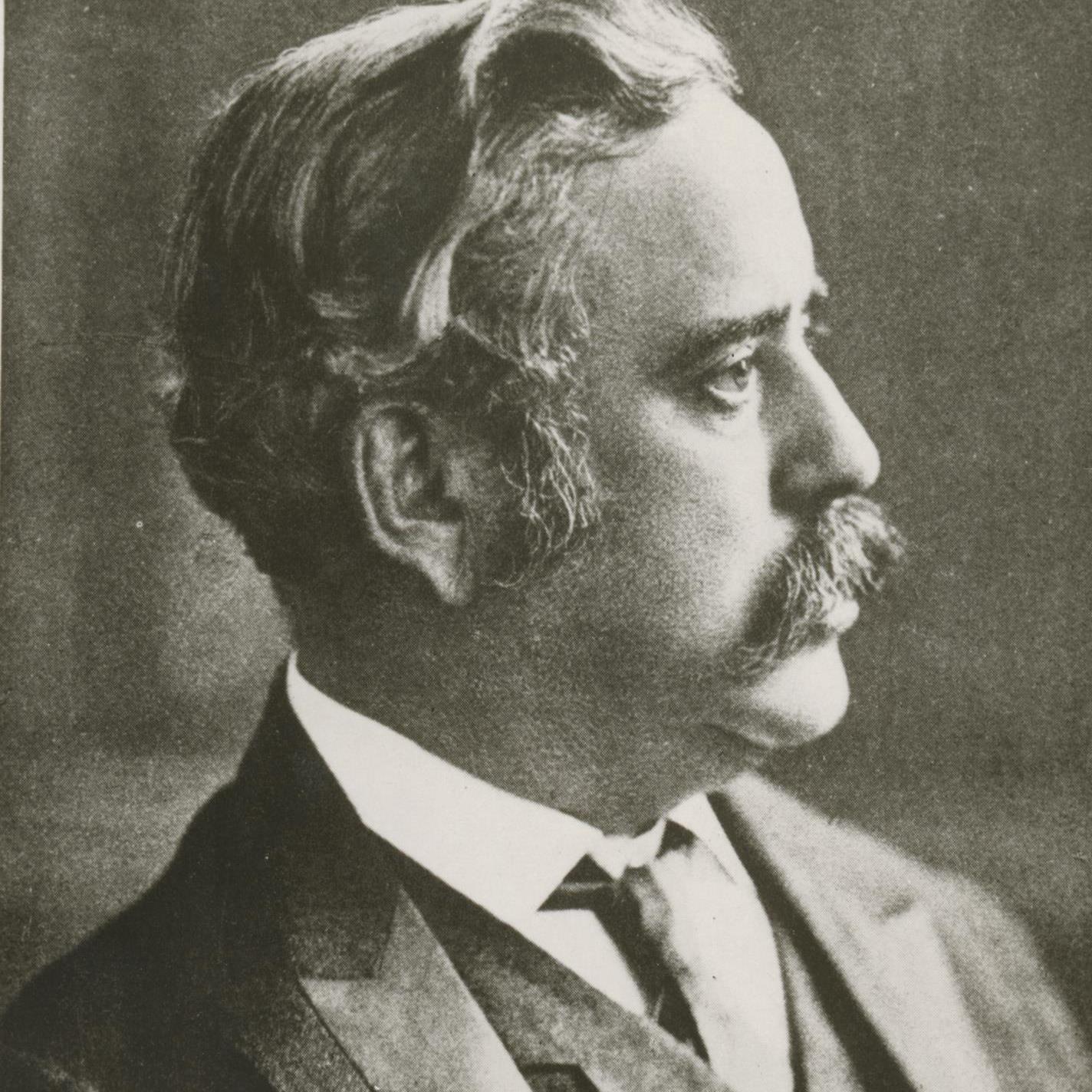 Black and white photograph of an older white man in an old-fashioned suit with a mustache