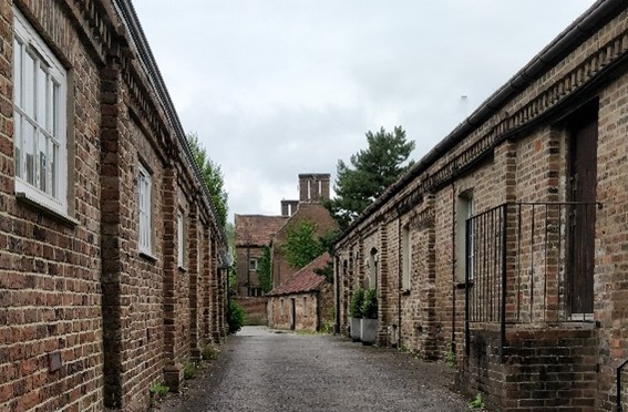 Passageway between single-storey red brick farm out buildings