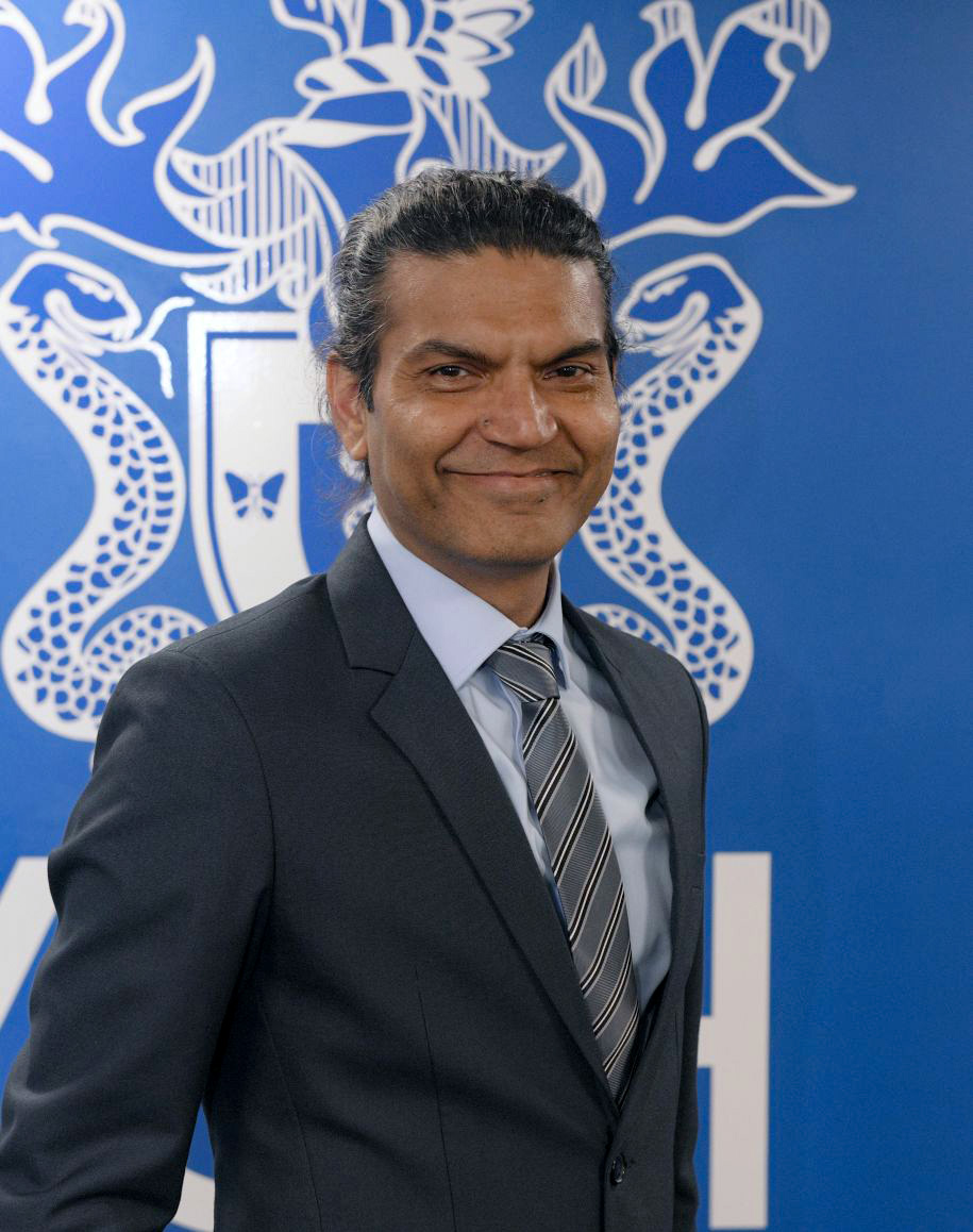 President Professor Subodh Dave wearing suit standing in front of RCPsych logo