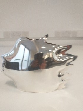 Silver sculpture shaped like a highly stylised head in portrait