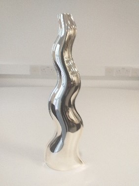 Silver sculpture shaped like a tall thin wavy line