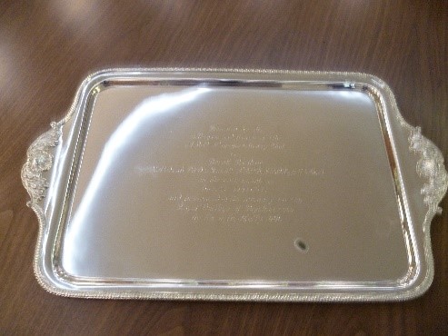 Silver tray with ornate edges and handles and engraving writing.